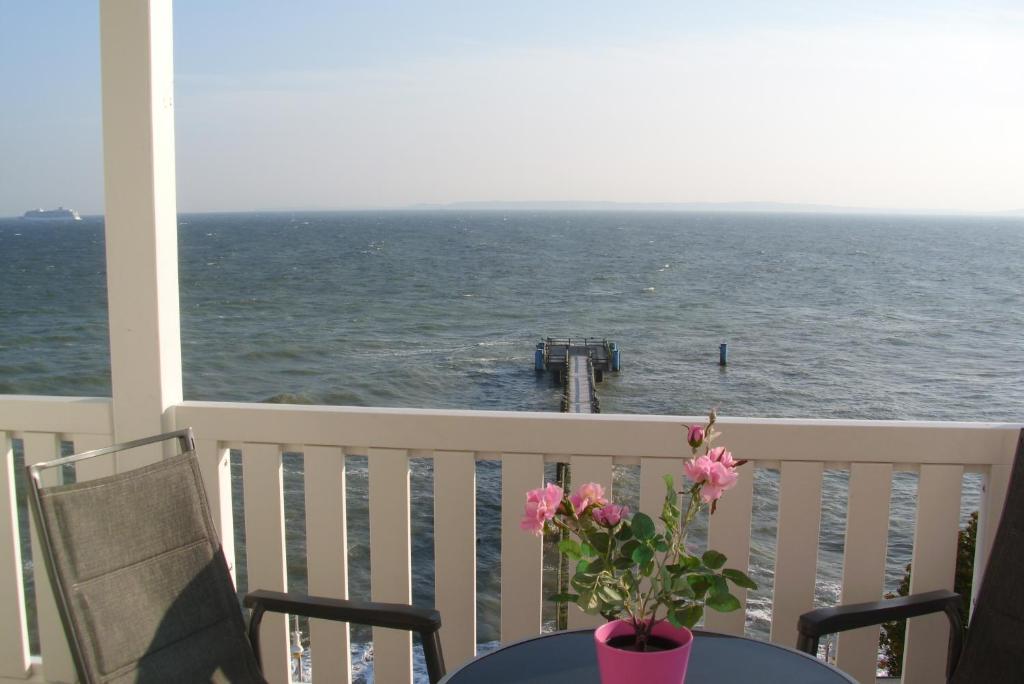 a table with a vase of flowers on a balcony with the ocean at Fürstenhof - Apartment 306 Victoria in Sassnitz