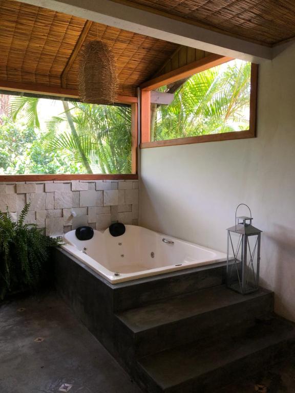 een bad in een kamer met 2 ramen bij Pousada Vila Piola in Guarda do Embaú