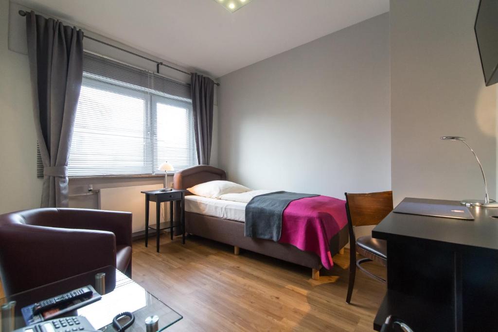 a bedroom with a bed and a desk and a window at Hotel Klein Frankfurt East in Frankfurt