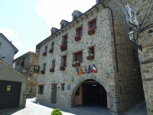 ein großes Steingebäude mit einem Torbogen mit Flaggen darauf in der Unterkunft Hotel Villa Russell in Torla-Ordesa