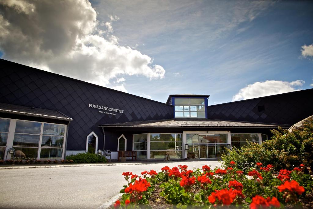 un edificio negro con flores rojas delante de él en Fuglsangcentret Hotel en Fredericia