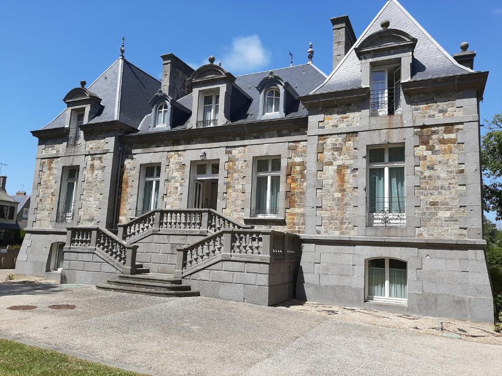 un gran edificio de piedra con escaleras delante en Manoir Le Castel & Villa Beaumaris en Saint-Malo