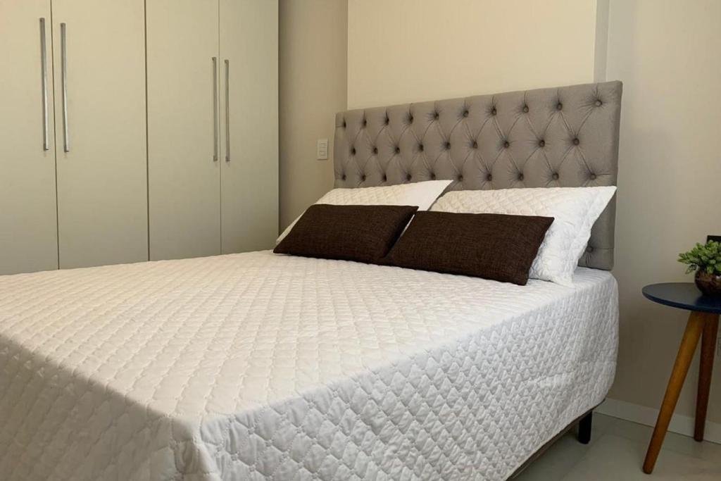 a bedroom with a white bed with a gray headboard at Suite Completa Master Collection in Passo Fundo