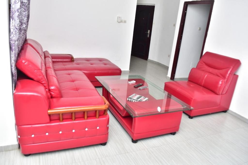 duas cadeiras vermelhas e uma mesa de vidro num quarto em E3G Sarl em Lomé