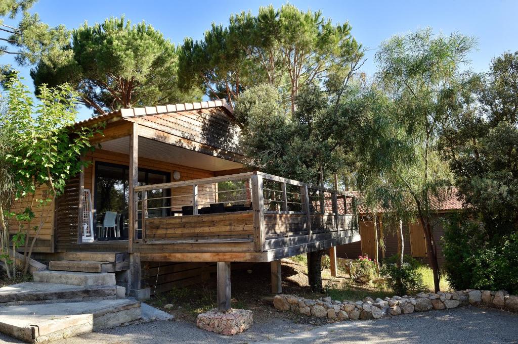 a house with a large deck in the woods at Résidence & Hotel U Livanti ECOLABEL in Propriano