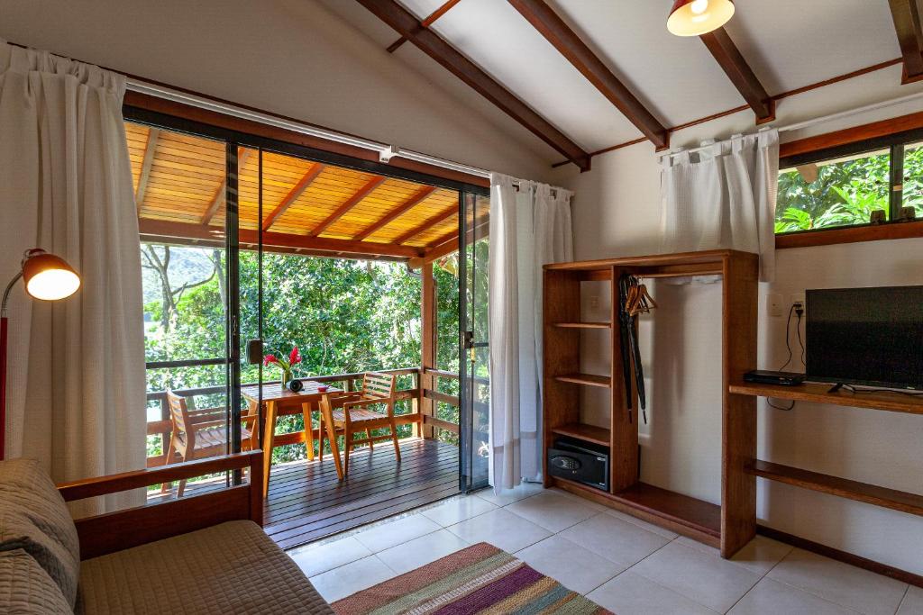 a living room with a television and a balcony at Atlantica Jungle Lodge in Abraão