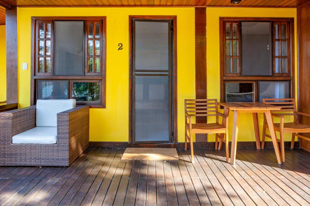 a yellow house with a table and chairs on a porch at Atlantica Jungle Lodge in Abraão