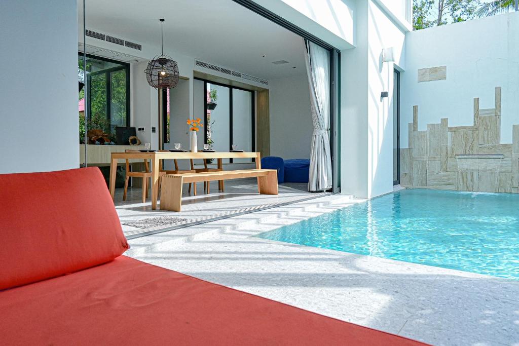 salon z czerwoną kanapą i basenem w obiekcie Chomdao Maikhao w mieście Ban Bo Sai Klang