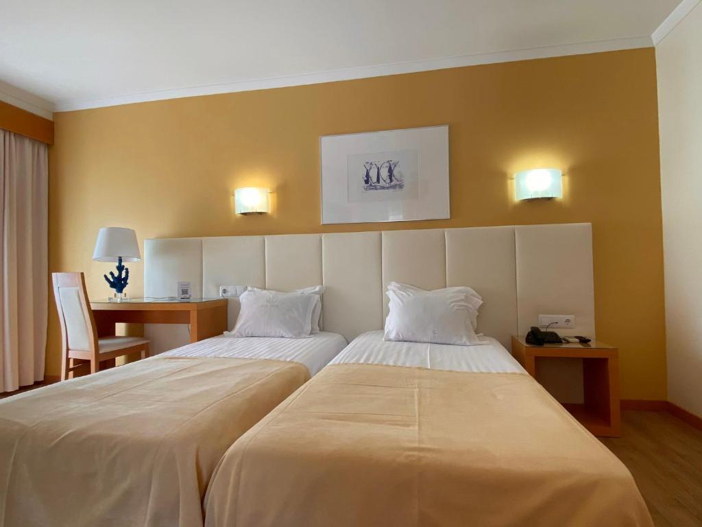 a hotel room with two beds and a desk at Hotel Mare in Nazaré