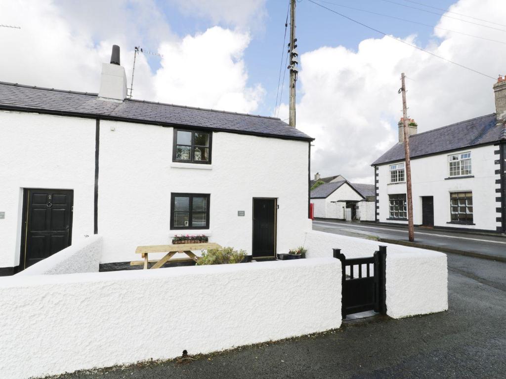 a white house with a bench in the street at Menai Cottage in Llanfairpwllgwyngyll