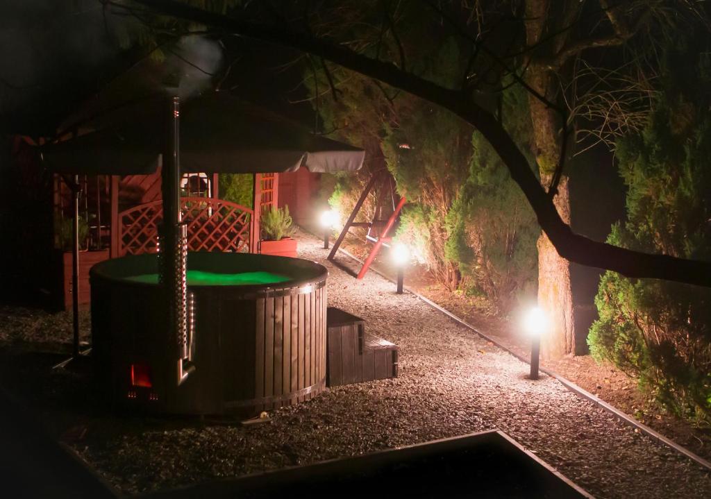 Domek nad Sanem في Zagórz: جلسة ليلية في حوض استحمام ساخن في حديقة مع أضواء