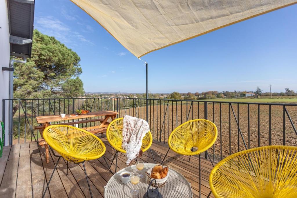 einen Balkon mit gelben Stühlen, einem Tisch und einem Tisch in der Unterkunft Le Cottage Nature Loin de l'oeil Clim Gaillac entre Albi-Toulouse & Les Cottages du Tarn in Brens