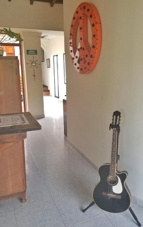 a guitar leaning against a wall next to a clock at Sam'S VIP Hostel San Gil in San Gil