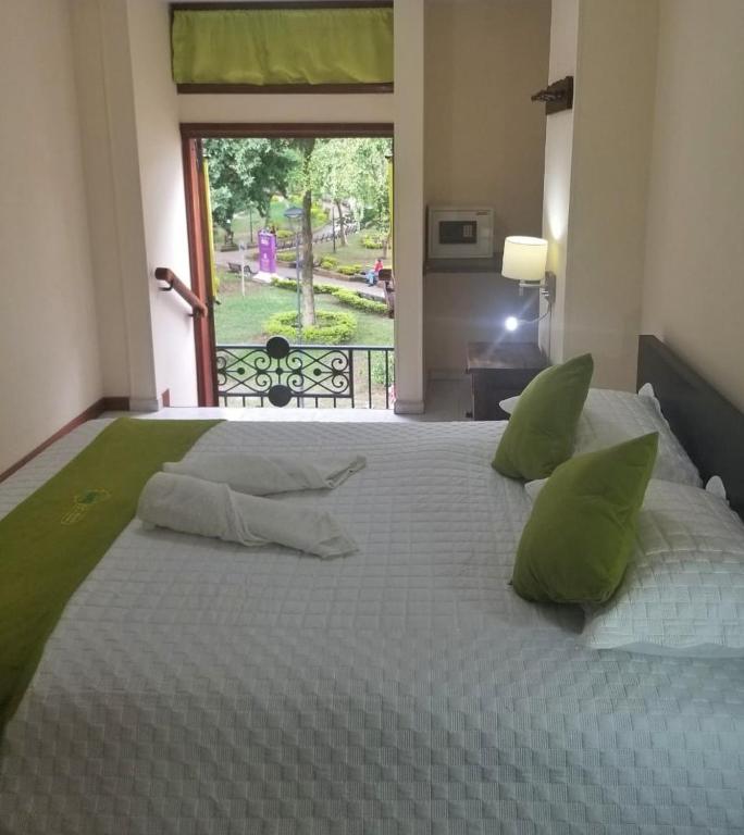 a large white bed with green pillows on it at Sam'S VIP Hostel San Gil in San Gil