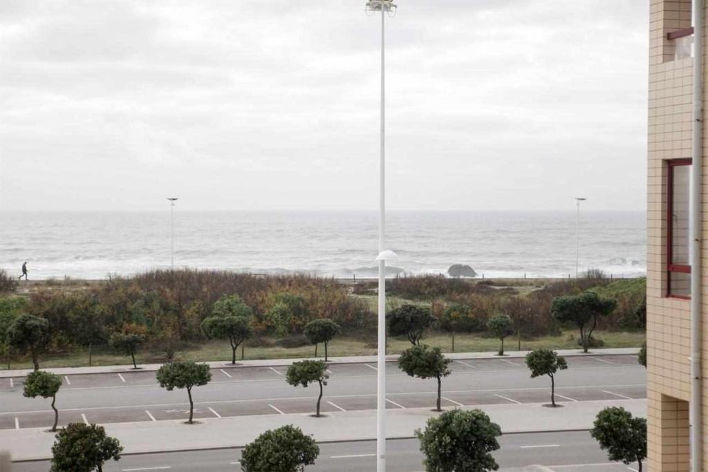 uma vista para um parque de estacionamento com o oceano ao fundo em Apartamento Edumar em Vila do Conde