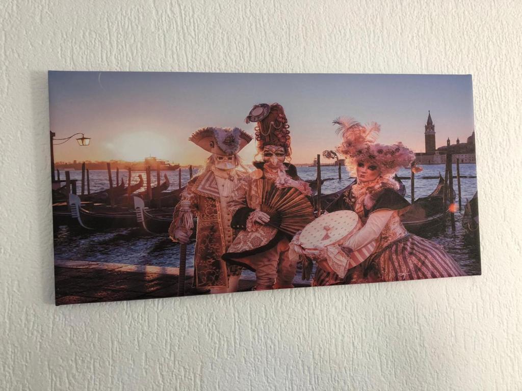a picture of three people in costumes on a wall at Venice Apartment in Interlaken