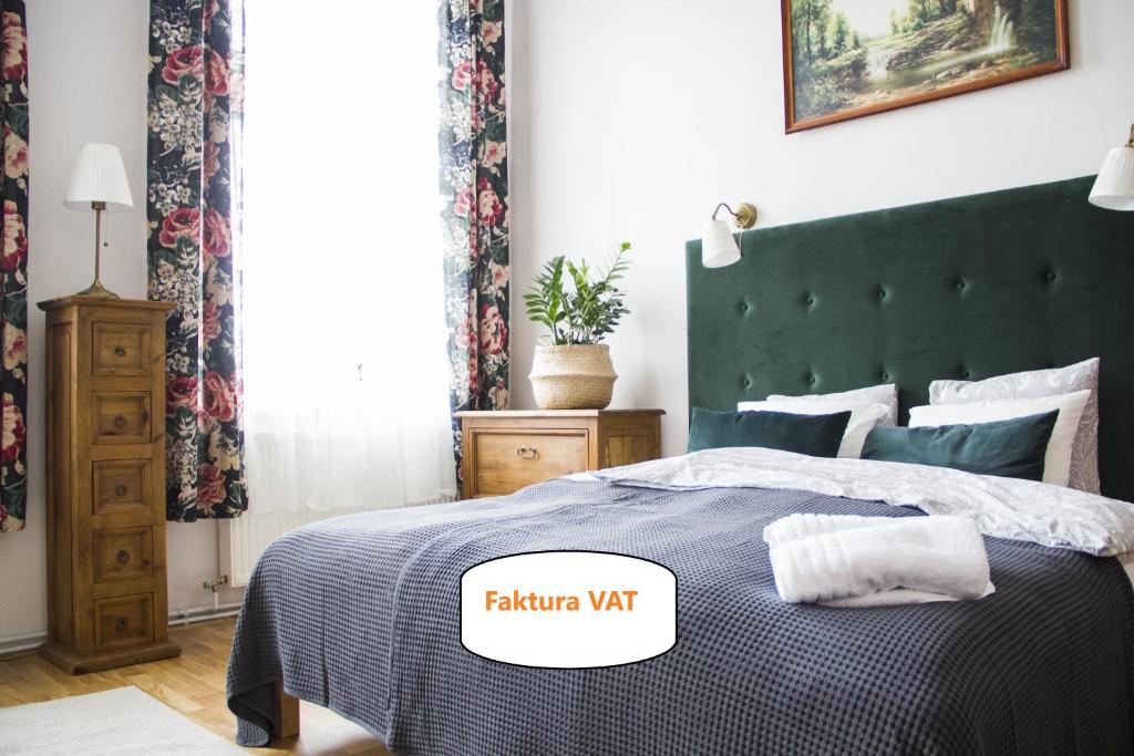 a bedroom with a bed with a dark green headboard at Apartamenty Stary Rzeszów in Rzeszów