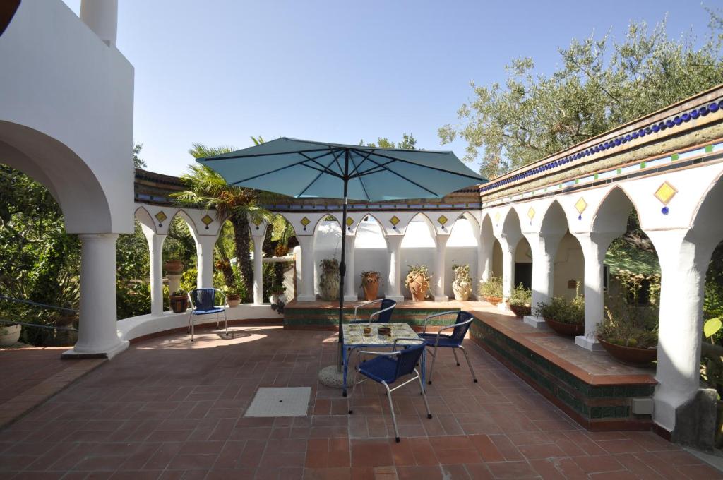 a patio with a table and chairs and an umbrella at Villa Eva in Anacapri
