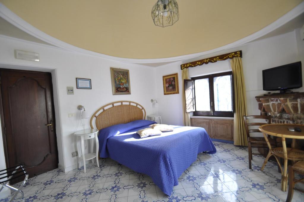 a bedroom with a bed with a blue blanket at Villa Eva in Anacapri
