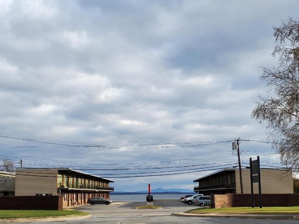 a parking lot with two buildings and a body of water at Golden Gate Lodging in Plattsburgh