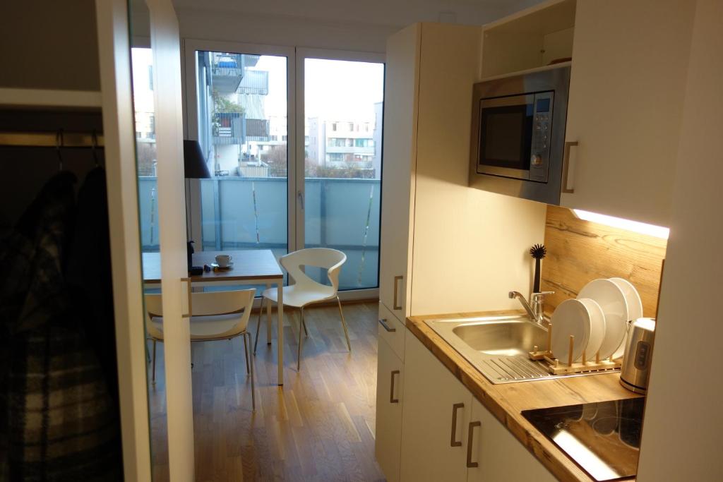una cucina con lavandino e tavolo con sedie di München-Riem my room Apartment an der Messe a Monaco