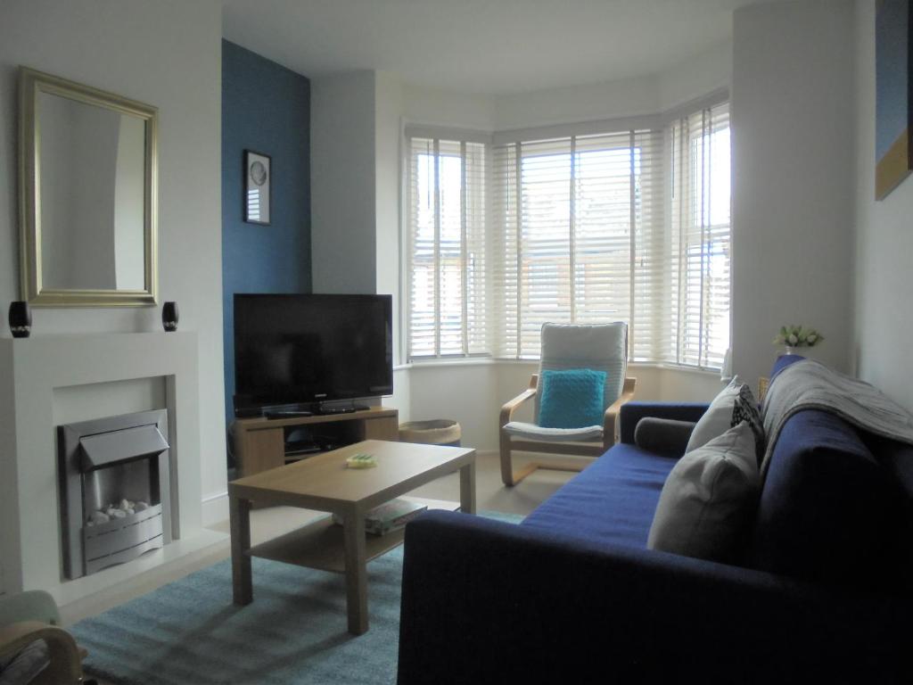 uma sala de estar com um sofá azul e uma televisão em 11B Beachside em Eastbourne