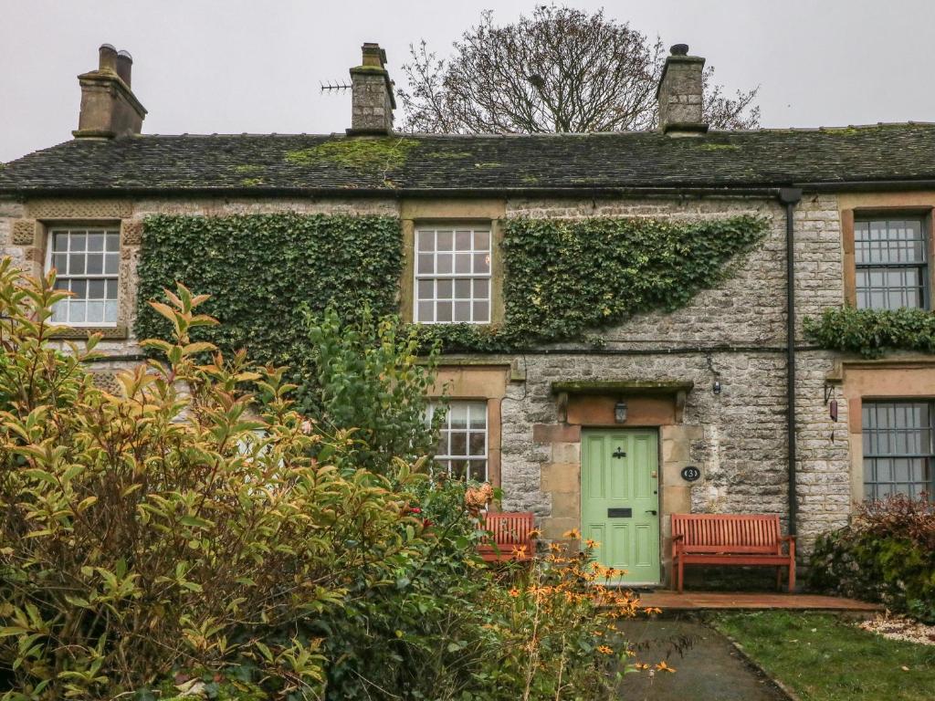 une ancienne maison en pierre avec une porte verte dans l'établissement 3 Old Hall Cottages, à Bakewell
