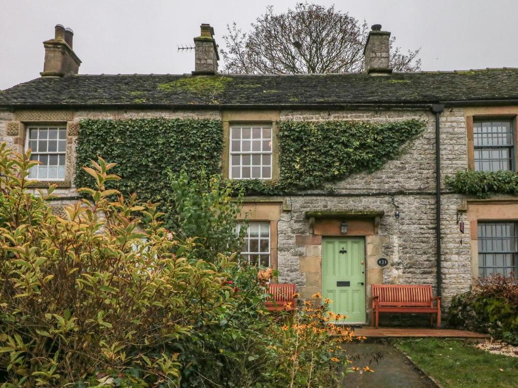 an old stone house with a green door at 3 Old Hall Cottages in Bakewell