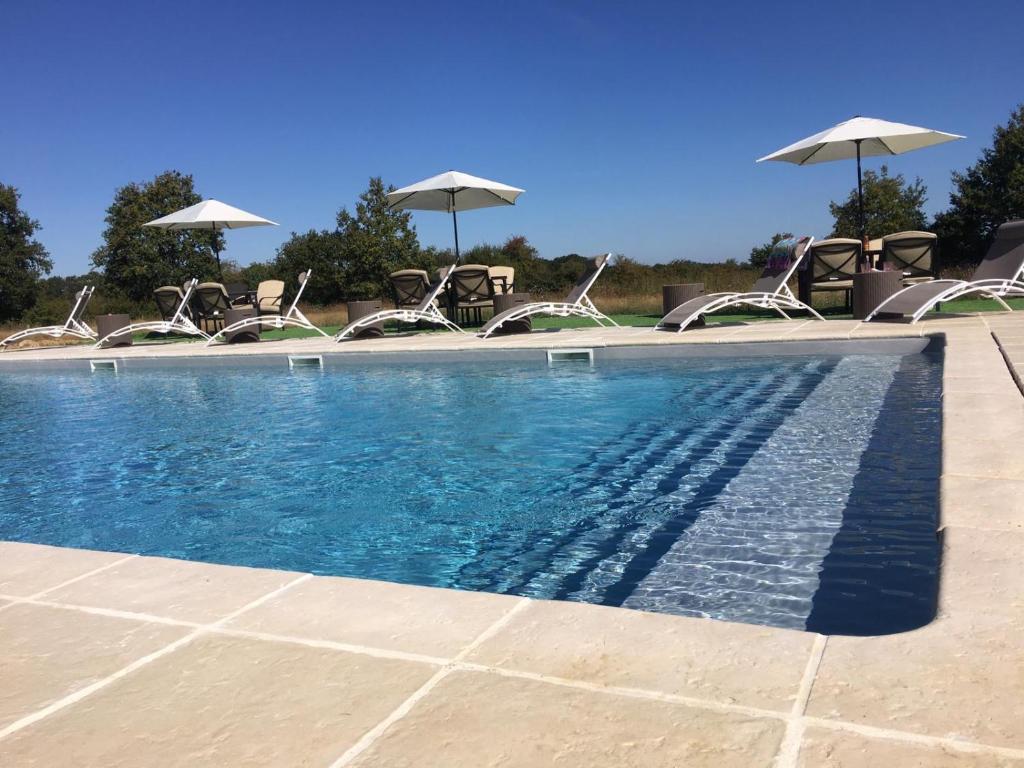 una piscina con sillas y sombrillas en Fonclaire Holidays en Mortemart