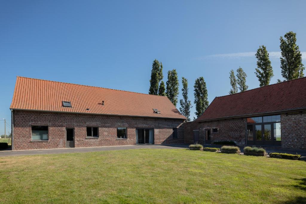 a brick building with a large yard in front of it at vakantiewoning onZENhof in Heuvelland