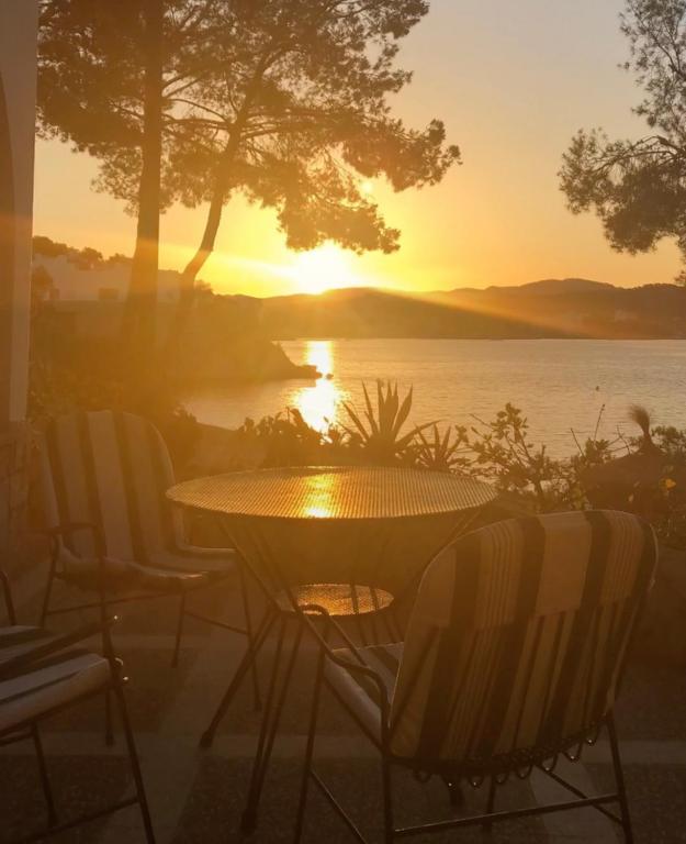 a table and chairs with a sunset in the background at Hotel Cala Fornells in Paguera