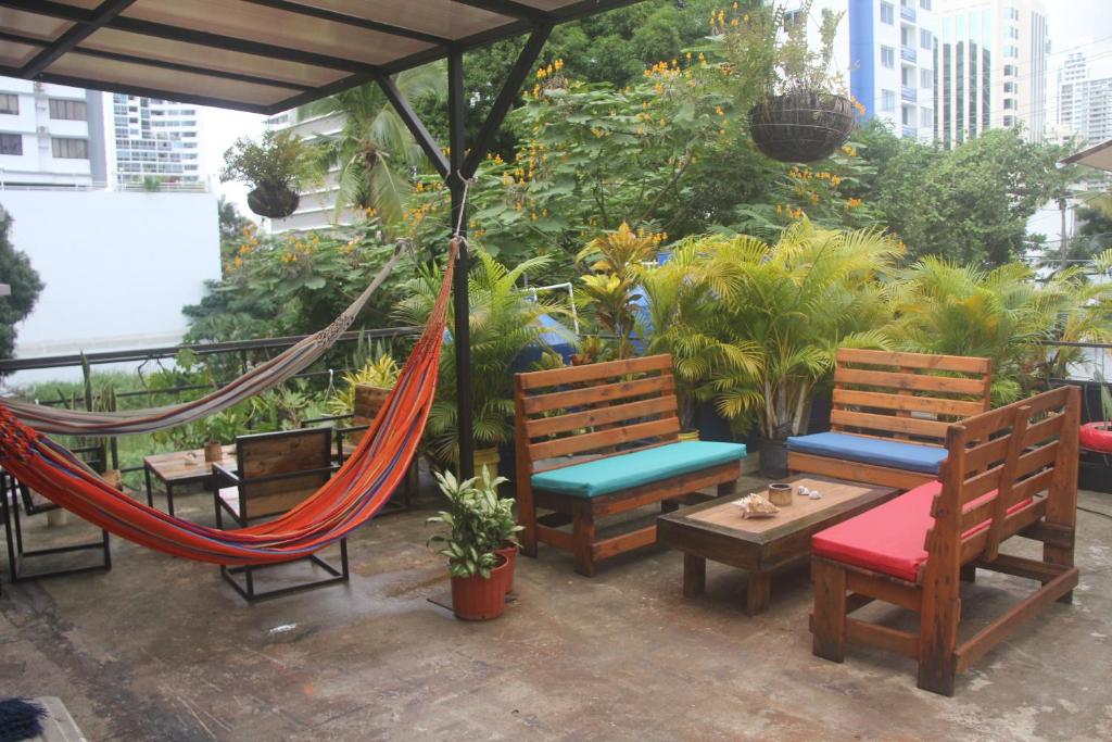 um pátio com dois bancos e uma rede de descanso em Eden`s Garden Hostel na Cidade do Panamá
