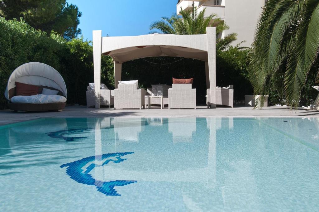 a swimming pool with chairs and a gazebo at Hotel Residence Stella del Mare in Vada