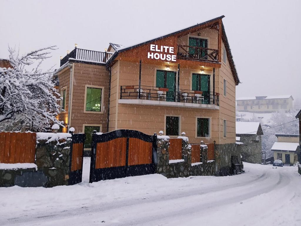 een gebouw met een bord dat staat voor elite huis in de sneeuw bij Hotel Elite House in Mestia