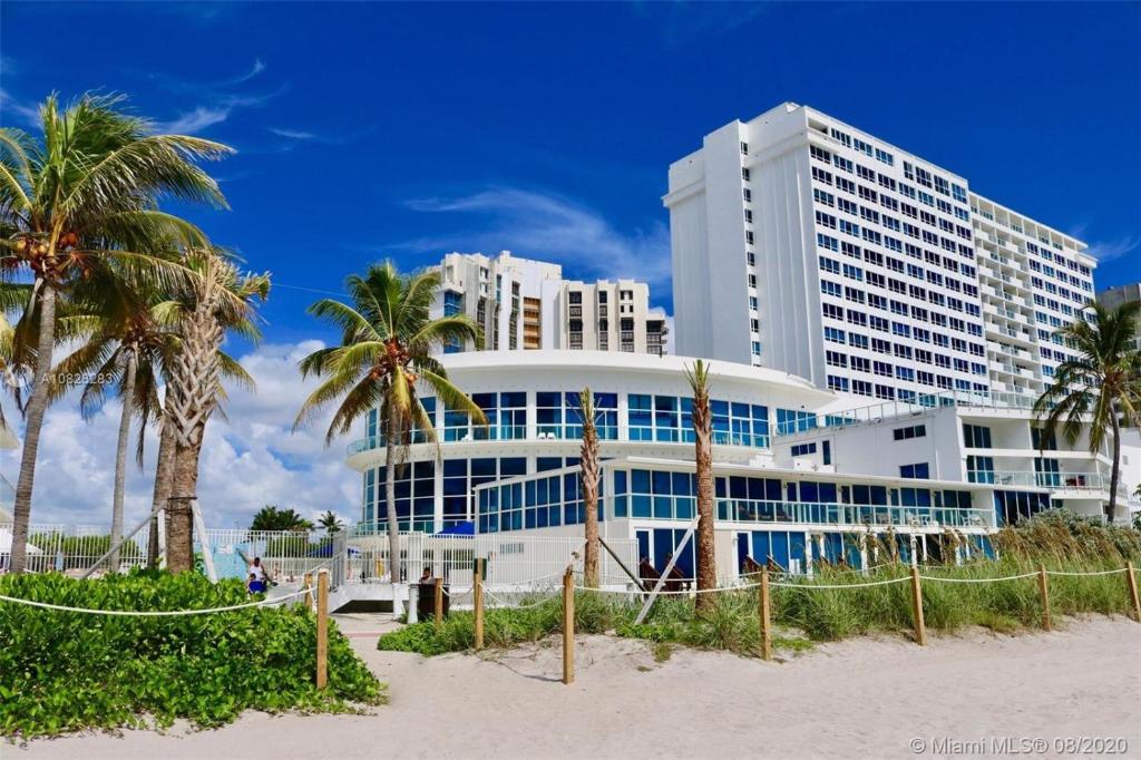 um grande edifício na praia com palmeiras em Girasole Apartments em Miami Beach