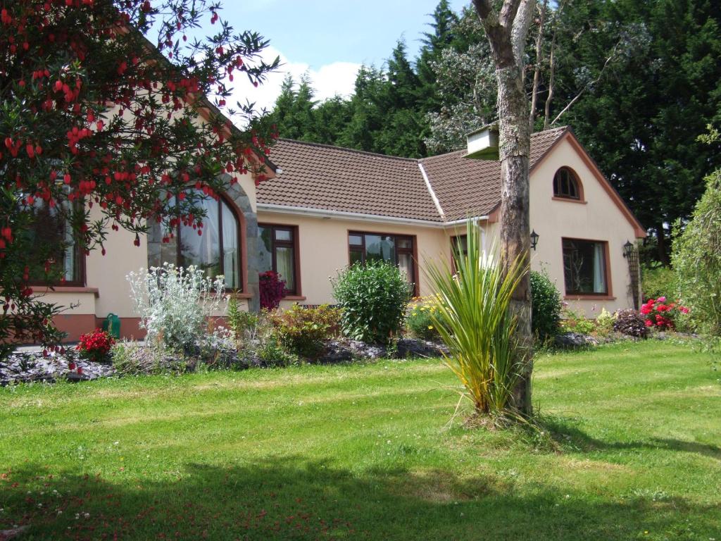 una casa con un césped verde delante de ella en O'Sheas Ceol Na Habhann B&B en Kenmare