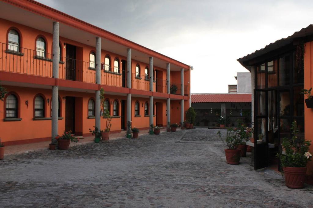 a courtyard of an orange building with potted plants at Villas Tonantzintla in Cholula