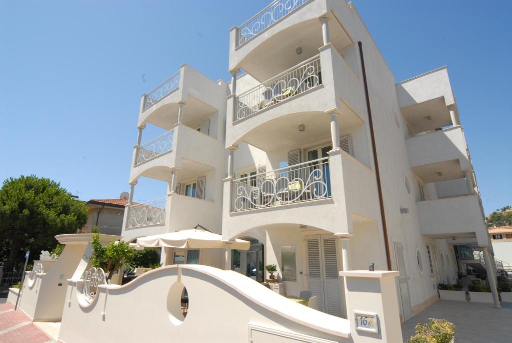 格羅塔姆馬雷的住宿－Residence Costa Smeralda，前面有一把伞的大型白色建筑