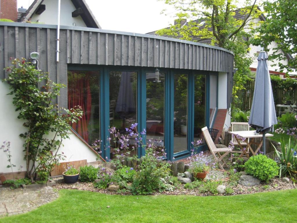 a conservatory with a table and an umbrella in a garden at Ferienhaus-in-Rotenburg in Rotenburg an der Wümme