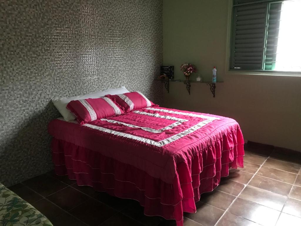 a bedroom with a bed with a pink blanket on it at Casa da waldir quarto suíte 01 in Goiás