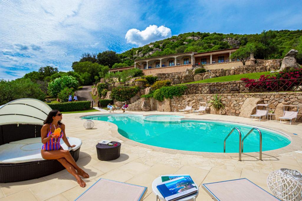 una mujer sentada en una silla junto a una piscina en Moma Hotel Cannigione, en Cannigione