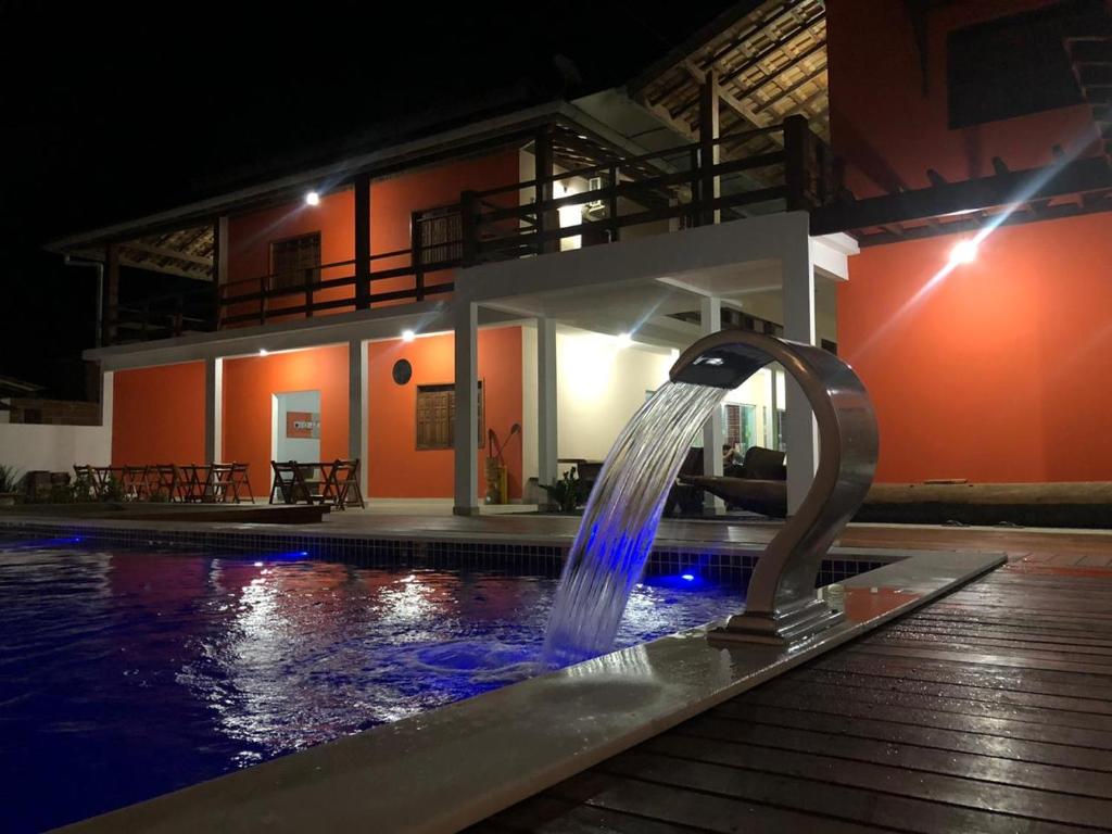 a water fountain in the middle of a pool at night at POUSADA TUPINAMBA in Ilha de Boipeba