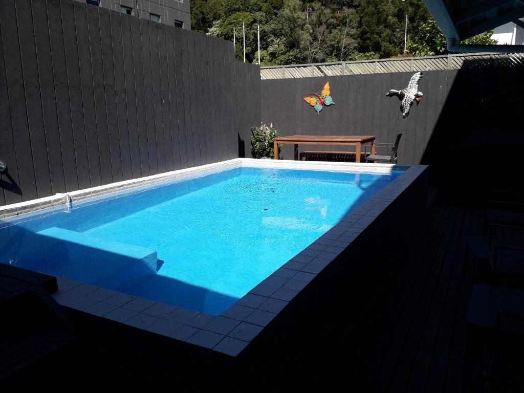 a blue swimming pool with a wooden table and a bench at Lake Lodge Motel Rotorua in Rotorua
