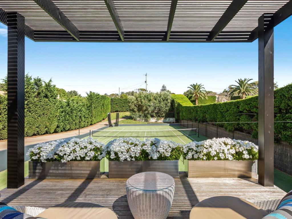 a patio with a tennis court and flowers at The Belmond in Portsea