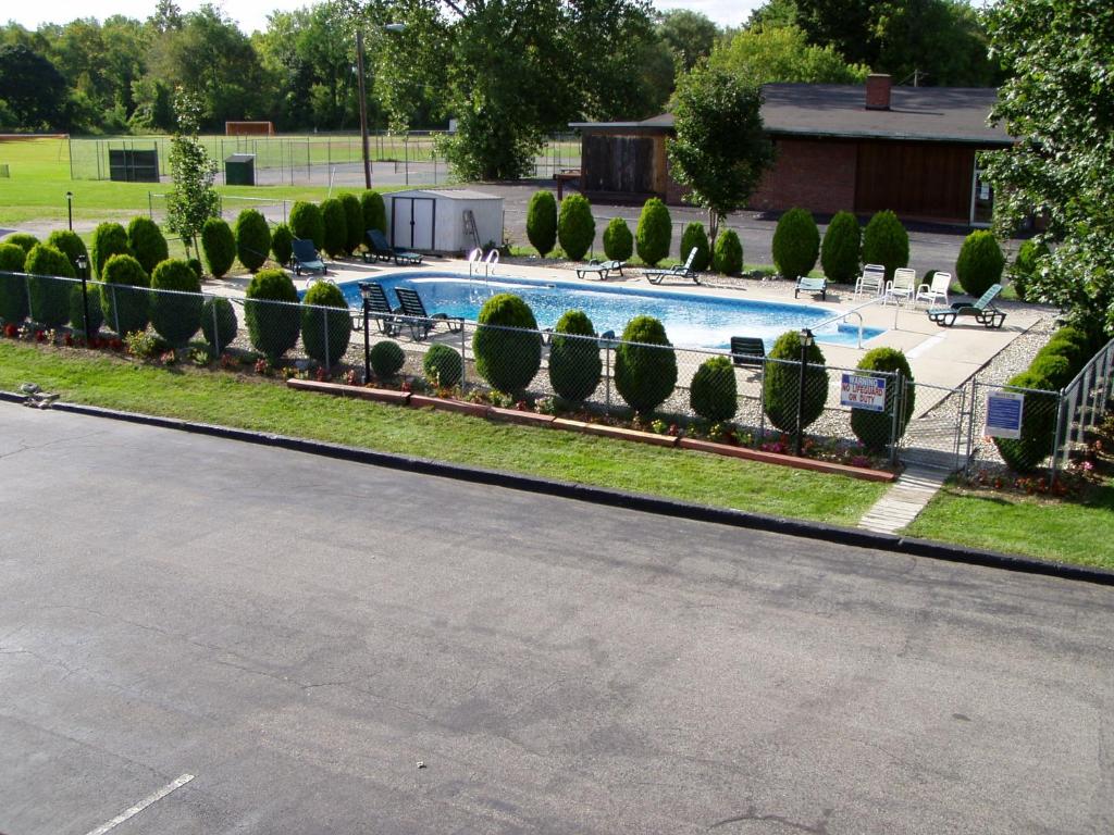 uma piscina com uma fileira de arbustos e árvores em Sunset Inn em Lee