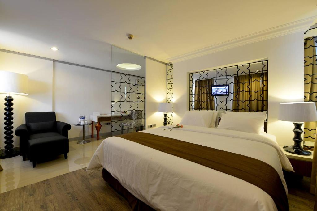 una camera con un grande letto e una sedia nera di The Naripan Hotel a Bandung