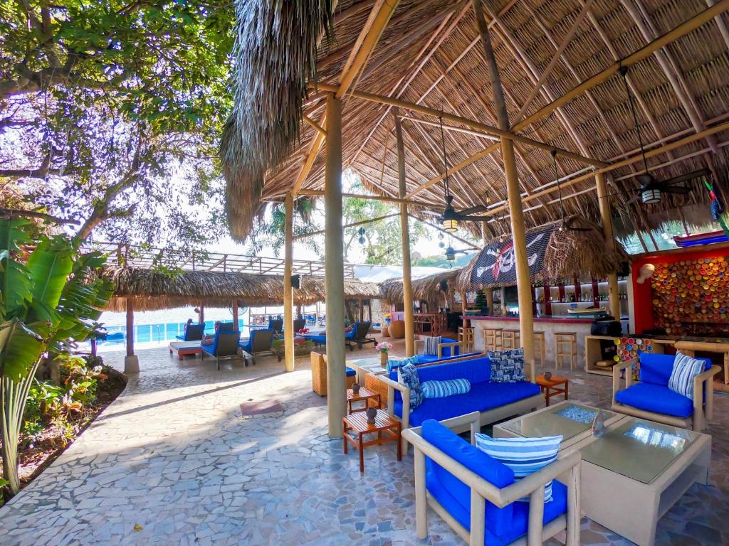 a restaurant with blue chairs and tables and a straw umbrella at Hotel Isla Real in Tierra Bomba