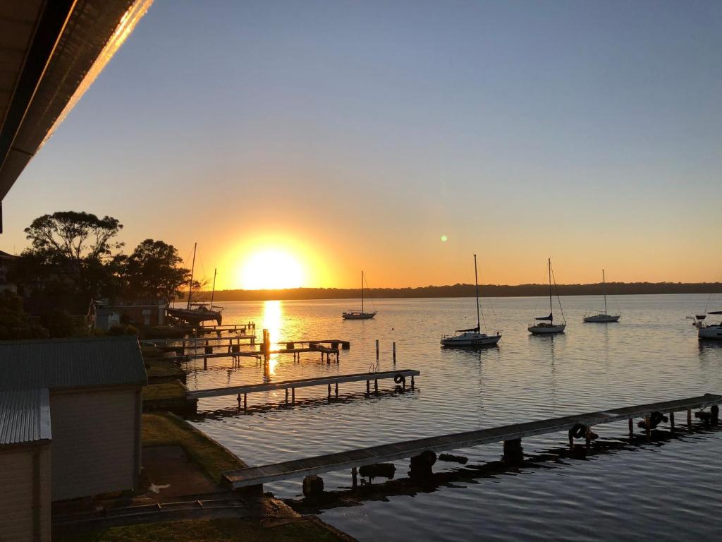 a sunset over a dock with boats in the water at The Boat House Absolute Waterfront and Jetty in Morisset East