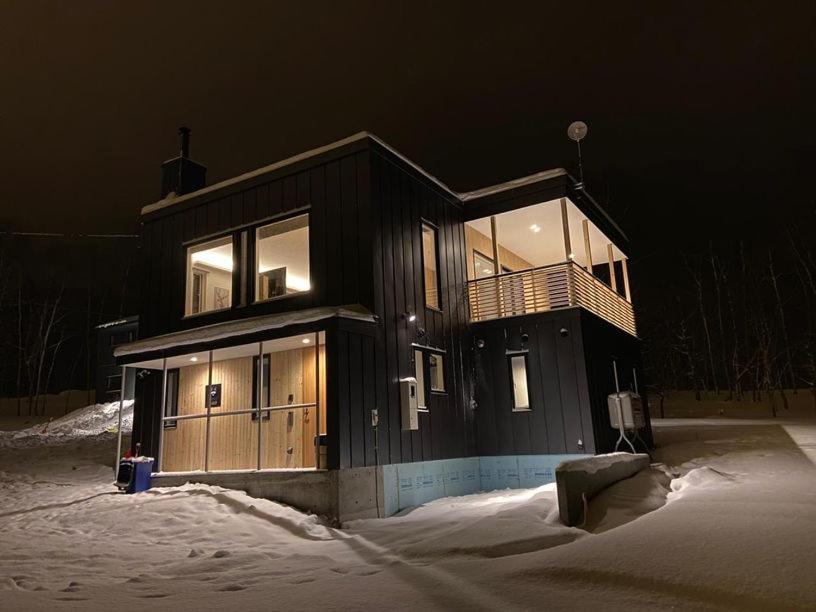 ein großes Haus im Schnee in der Nacht in der Unterkunft Tanuki House in Rusutsu