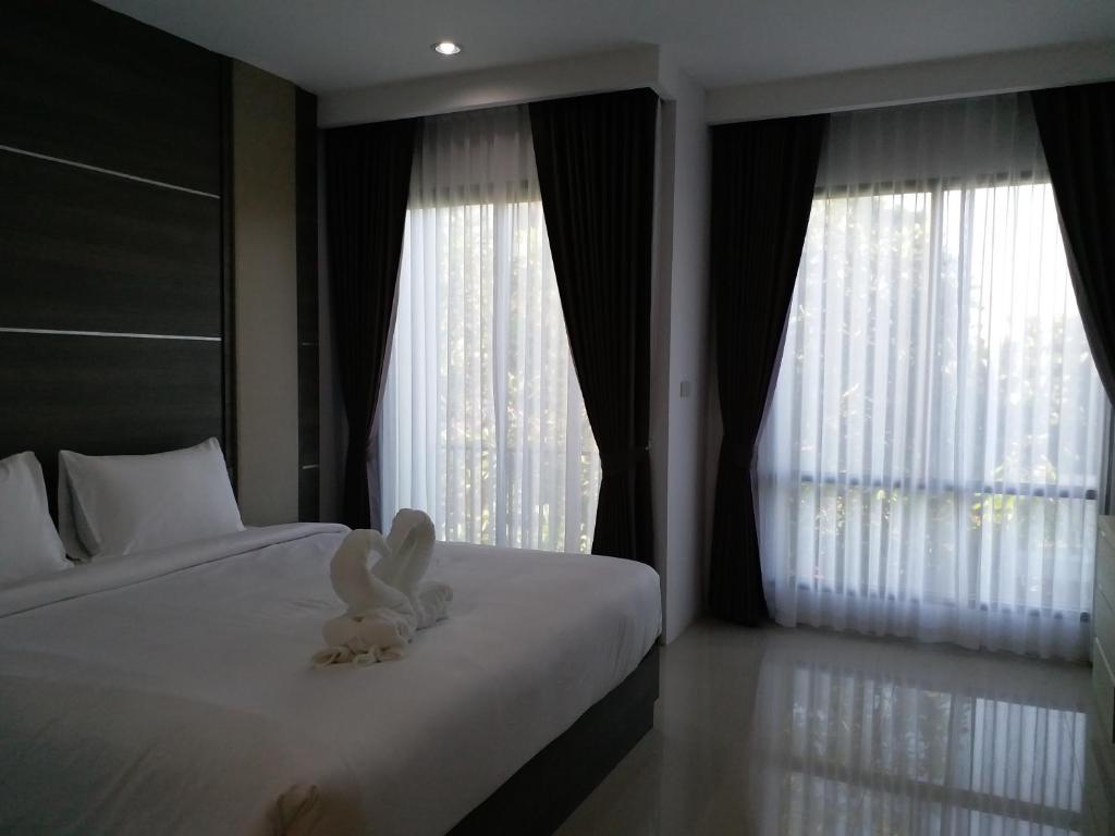 a white bunny sitting on a bed in a bedroom at Areena Hotel Phitsanulok in Phitsanulok